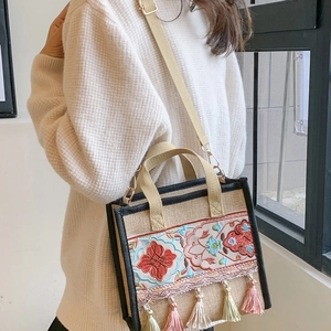 Detail of ethnic embroidered tote bag with pink and green tassels and woven strap
