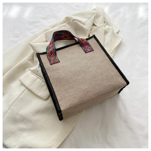 Détail du sac seau en jute ethnique avec bandoulière géométrique sur un blazer