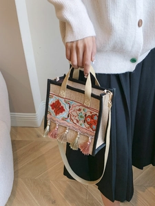 Detail showing ethnic style floral embroidery and tassel on the beige canvas tote bag