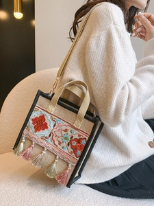 Detail of ethnic embroidered handbag with colorful tassels and black woven strap