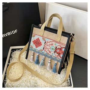 Detail of ethnic canvas handbag with floral embroidery and colorful tassels in a gift box