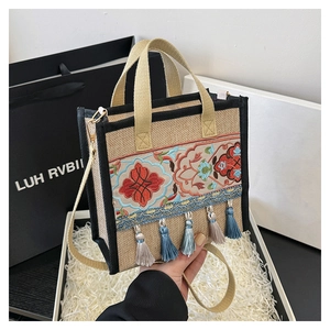 Detail of ethnic embroidery and tassels on a woven handbag inside a gift box