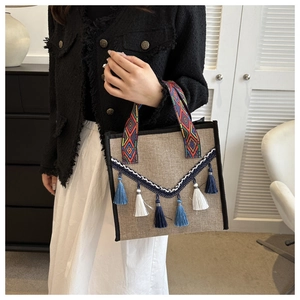 Détail du sac seau en toile de jute bohème avec poignées tissées et pompons en coton bleu