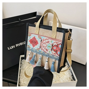 Detailed close-up of ethnic embroidery and colorful tassels on the linen handbag surface