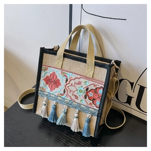 Detail of ethnic embroidery and colorful tassels on jute tote bag at 45-degree angle