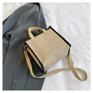 Detail of retro linen tote bag with black trim and tassel on a grey blazer