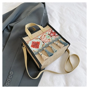 Detailed shot of ethnic embroidery and colorful tassels on a beige canvas tote bag