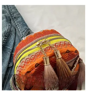 Close-up of smooth dual metal zippers and colorful tassels on woven crossbody bag