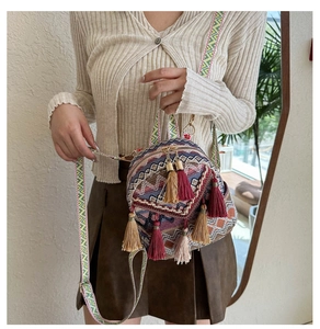 Close-up of bohemian mini crossbody bag with ethnic patterns and burgundy tassels