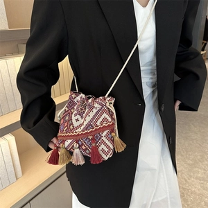 Detalle de bolso saco bohemio con tejido geométrico colorido y borlas decorativas