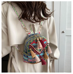Close-up of bohemian embroidered mini backpack with colorful tassels and jacquard strap