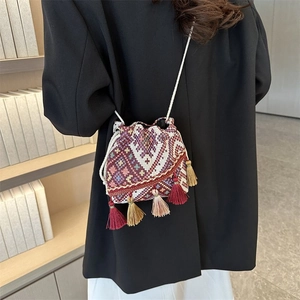 Primer plano de bolso tipo cubo étnico con estampados jacquard y detalles de flecos largos