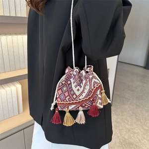Detalle de bolso saco étnico colorido con borlas bohemias y correa de hombro tejida