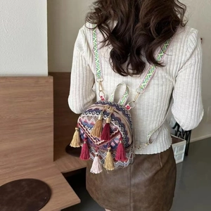 Detailed back view of ethnic jacquard backpack with colorful tassels and wide woven strap