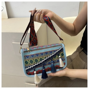Détail d'un sac à bandoulière bohème tissé avec broderies vintage et pompons ethniques