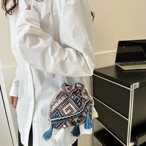 Primer plano detallado del bolso de cubo tejido étnico con borlas y patrones geométricos