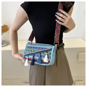 Détail de sac bandoulière bohème avec broderie colorée et pompons à franges