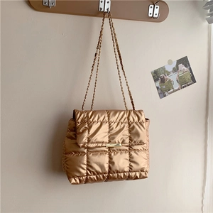 Gold quilted puffer shoulder bag with chain strap hanging on a wall hook