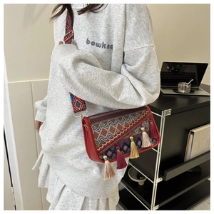 Détail du sac bandoulière bohème avec broderie ethnique et breloques à pompons