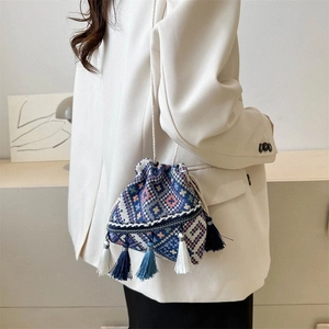 Bolso saco de tejido étnico con borlas coloridas y motivos geométricos en una modelo