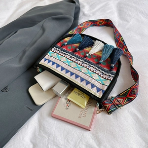 Bolso bandolera étnico con bordado borlas de colores y correa ancha de tejido trenzado