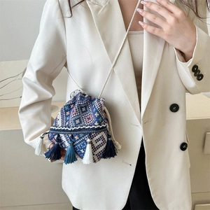 Detalle de bolso tipo saco tejido étnico con patrones coloridos y flecos largos decorativos