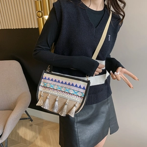 Ethnic embroidered crossbody bag with boho tassels and geometric patterns on canvas