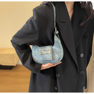 Detail of light blue crescent shoulder bag with gold buckle on black blazer