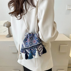 Detalle del bolso de cubo étnico con estampados geométricos y borlas azules para mujer