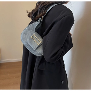 Chic grey crescent shoulder bag with metallic buckle shown in a stylish interior setting