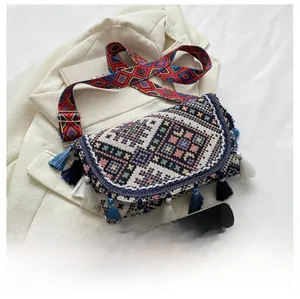 Détail d'un sac bandoulière bohème tissé avec motifs géométriques colorés et franges