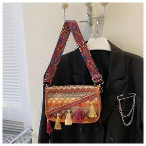 Détail d'un sac ethnique brodé avec des franges colorées et une bandoulière tissée
