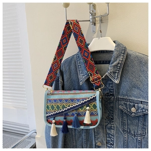 Détail d'un petit sac carré bohème avec broderies colorées et pompons bleus doux