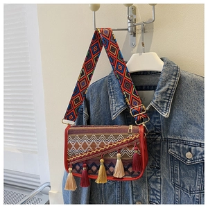 Détail d'un sac bohème tissé avec des glands colorés et une bandoulière brodée