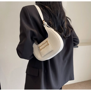 Detailed side view of white crescent hobo bag with gold buckle on black blazer