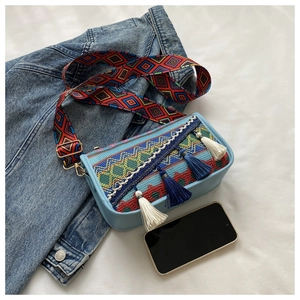 Mini sac bohème à pompons et bandoulière brodée, présenté à côté d'un smartphone