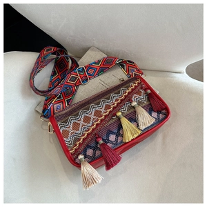 Détail du sac bohème avec pompons colorés et bandoulière aux motifs ethniques