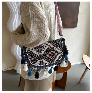 Détail d'un sac bandoulière bohème avec broderies géométriques et pampilles multicolores