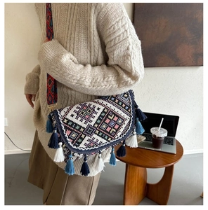 Détail d'un sac bandoulière ethnique avec broderies géométriques et pompons longs