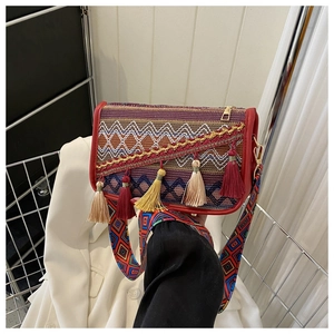 Détail du sac brodé ethnique avec pompons colorés et bandoulière tissée géométrique