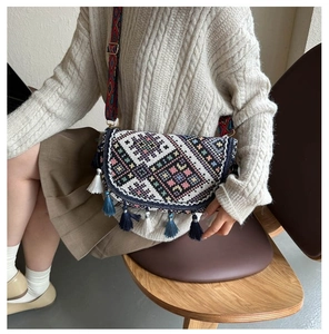 Détail d'un sac bohème tissé avec glands colorés et large bandoulière à motifs variés