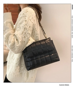 Détail d'un sac à bandoulière matelassé noir avec chaîne dorée dans un cadre mode stylé