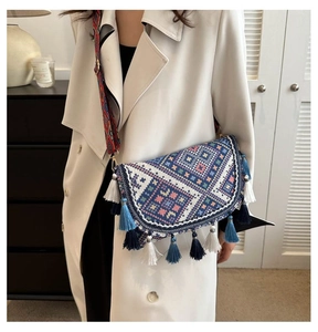 Détail d'un sac bandoulière tissé ethnique avec des glands colorés et une large bandoulière