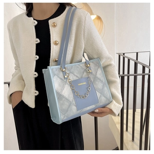Detail view of checkerboard tote bag with golden floral chain and blue leather patch pocket