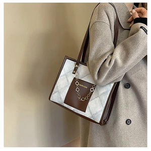 Detail of quilted tote bag featuring contrast leather trim and chic floral chain ornament