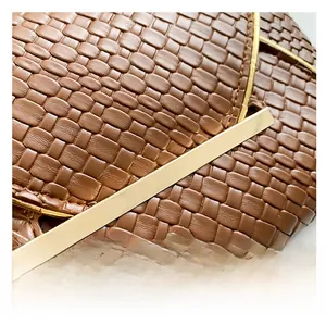 Dettaglio di pochette in pelle intrecciata marrone con finiture in metallo dorato