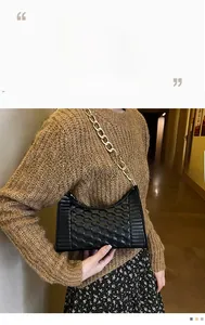 Detail of black crescent armpit bag with textured diamond pattern and chunky gold chain