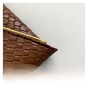 Dettaglio della trama in pelle intrecciata marrone scuro con bordo in metallo dorato