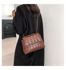 Détail de la texture en cuir matelassé marron et chaîne dorée d'un sac bandoulière