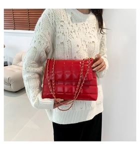 Détail du sac à bandoulière en similicuir rouge matelassé avec chaîne dorée élégante